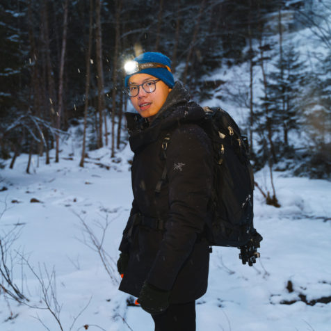 man with flashlight on the head in a winter forest with snow, student Leon