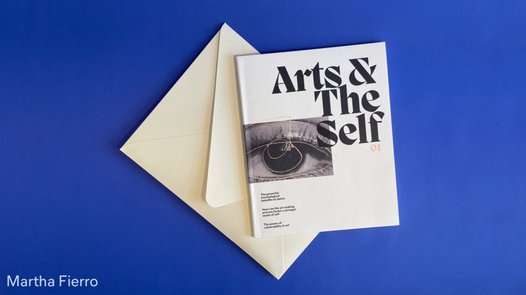 magazine cover titled arts & the self, close to an envelope in a blue background, by Martha Fierro