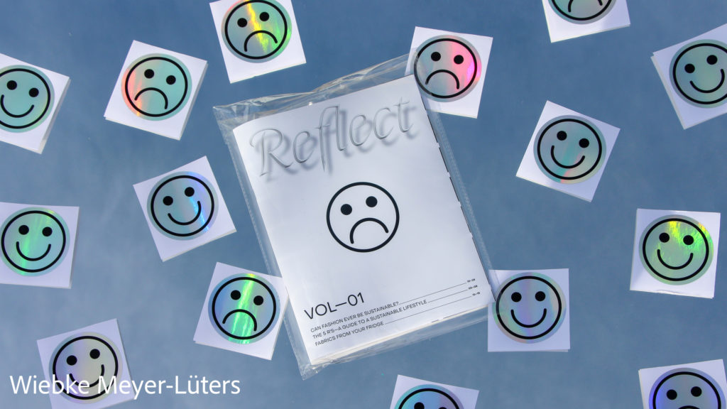 magazine inside a plastic titled reflect surrounded by stickers with happy and sad emojis, by wiebke meyer-luters