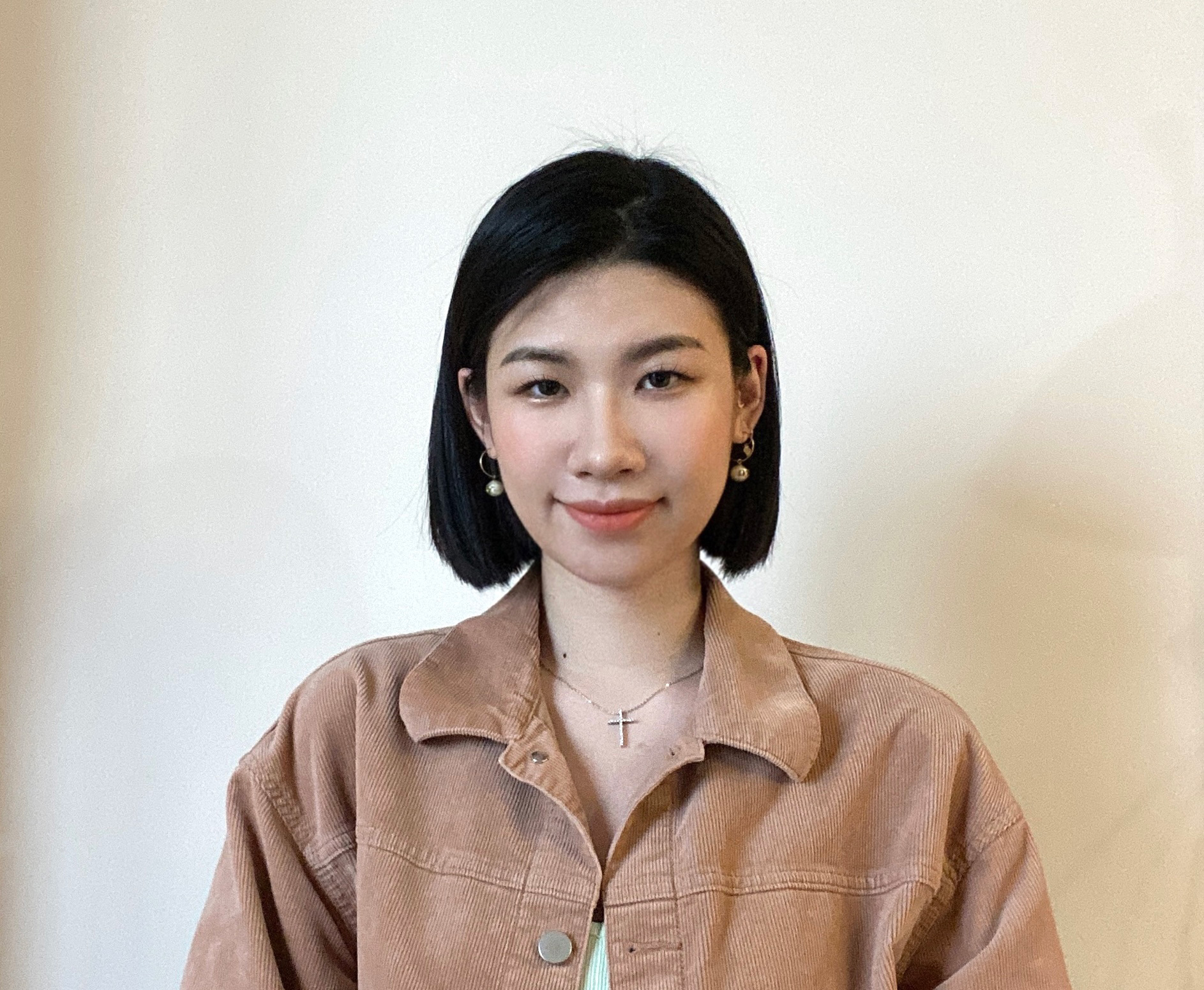 A photo of a woman wearing a necklace and a brown coat.