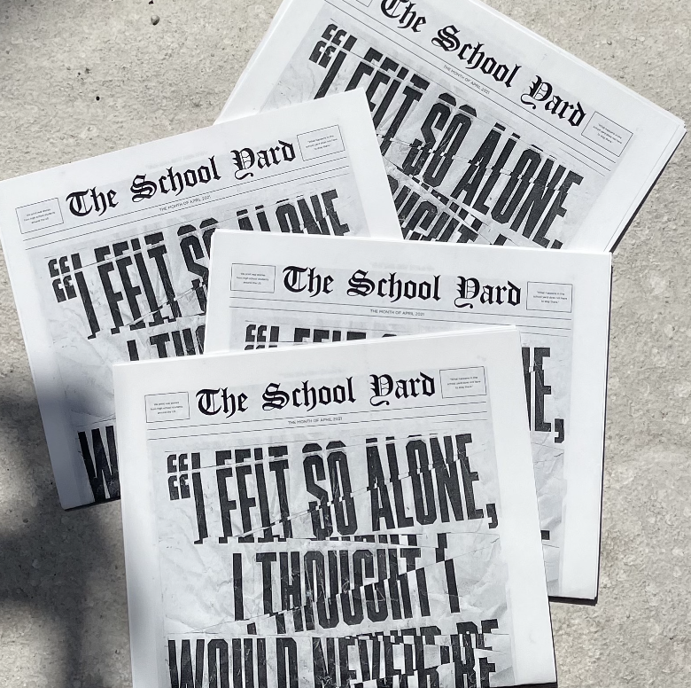 A photo of some news papers spread on concrete. The title says: The School Yard.