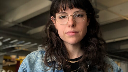 A photo of a woman wearing glasses and a jean jacket.