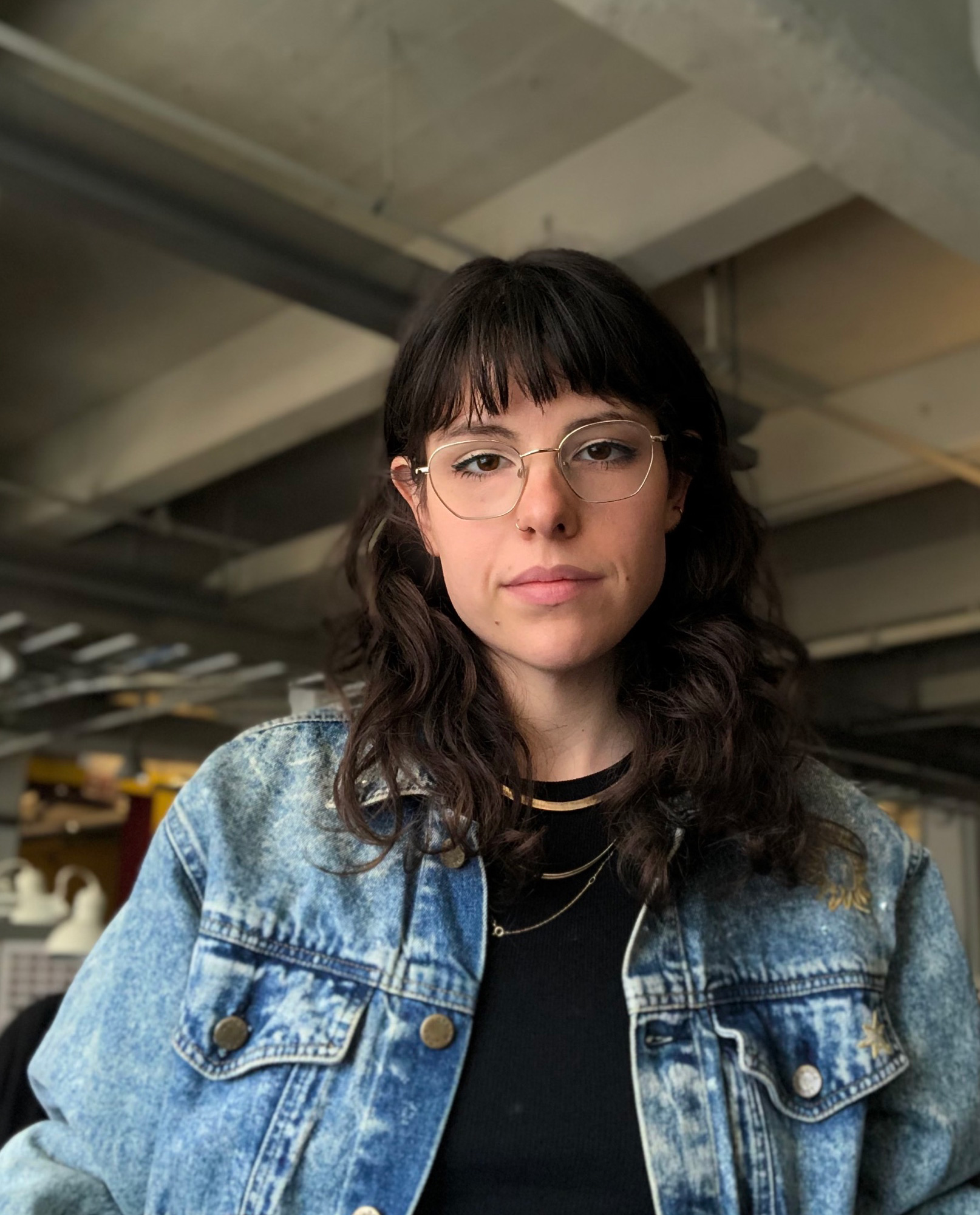 A photo of a woman wearing glasses and a jean jacket.