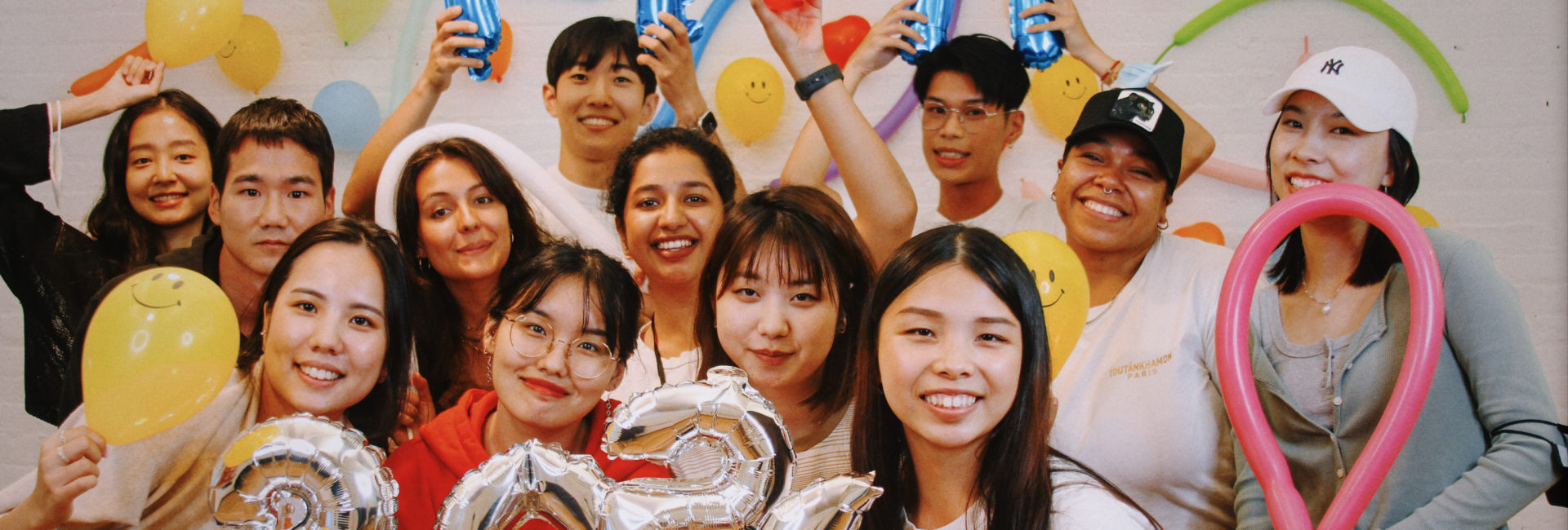 group of students holding balloons in front of colorful wall