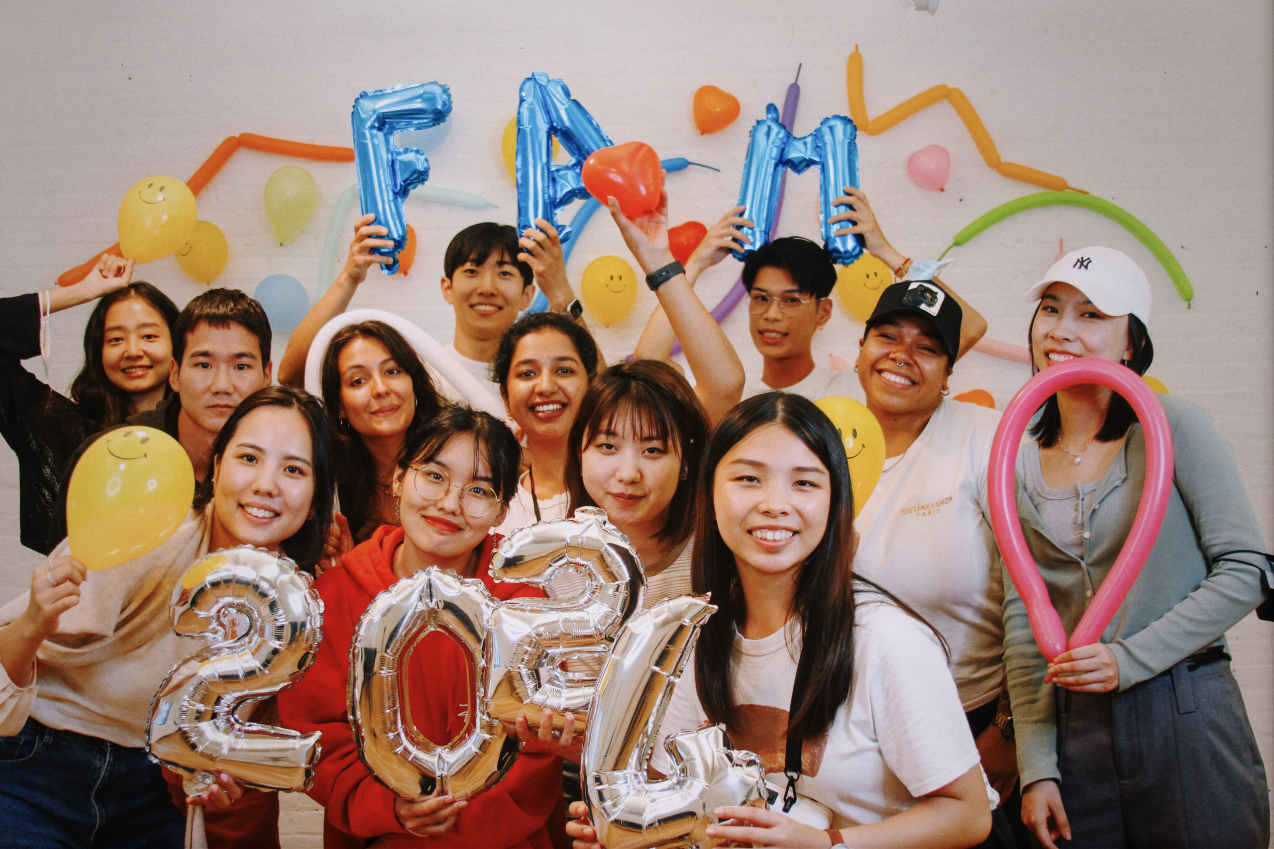 group of students holding balloons in front of colorful wall