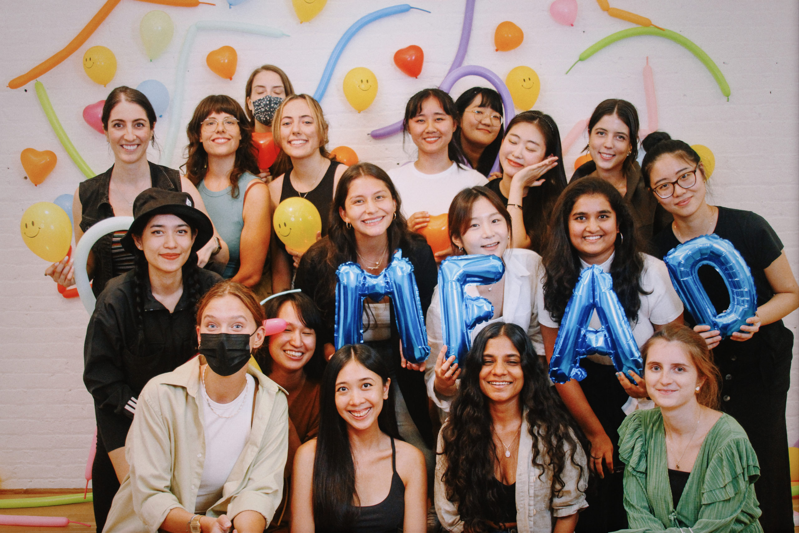 group of students holding balloons in front of colorful wall