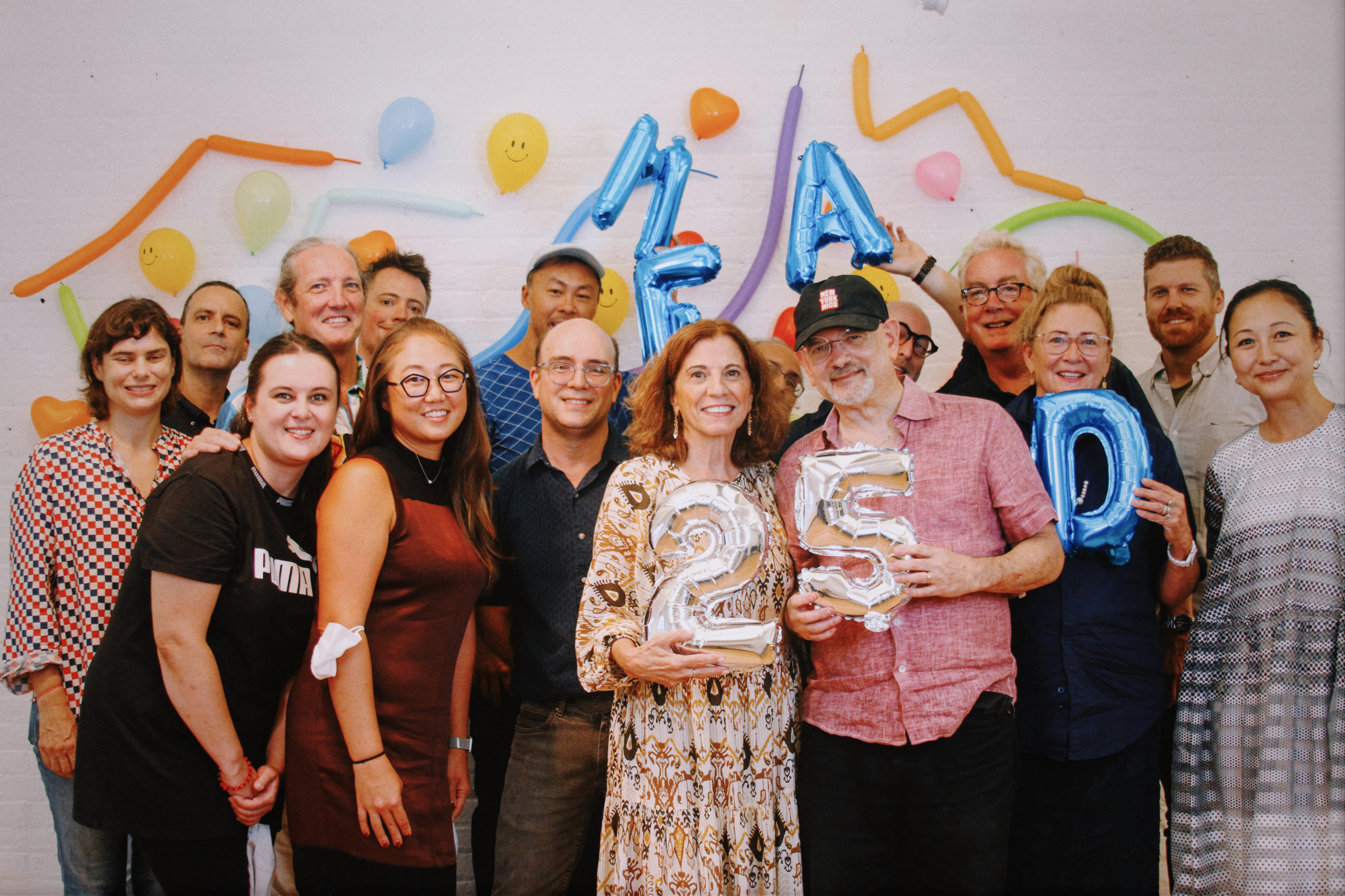 group of teachers holding balloons in front of colorful wall