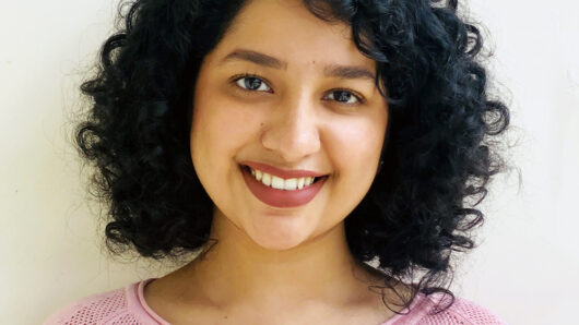 Indian Woman with curly hair and prink shirt