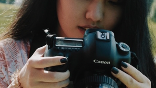 asian woman holding camera in the nature