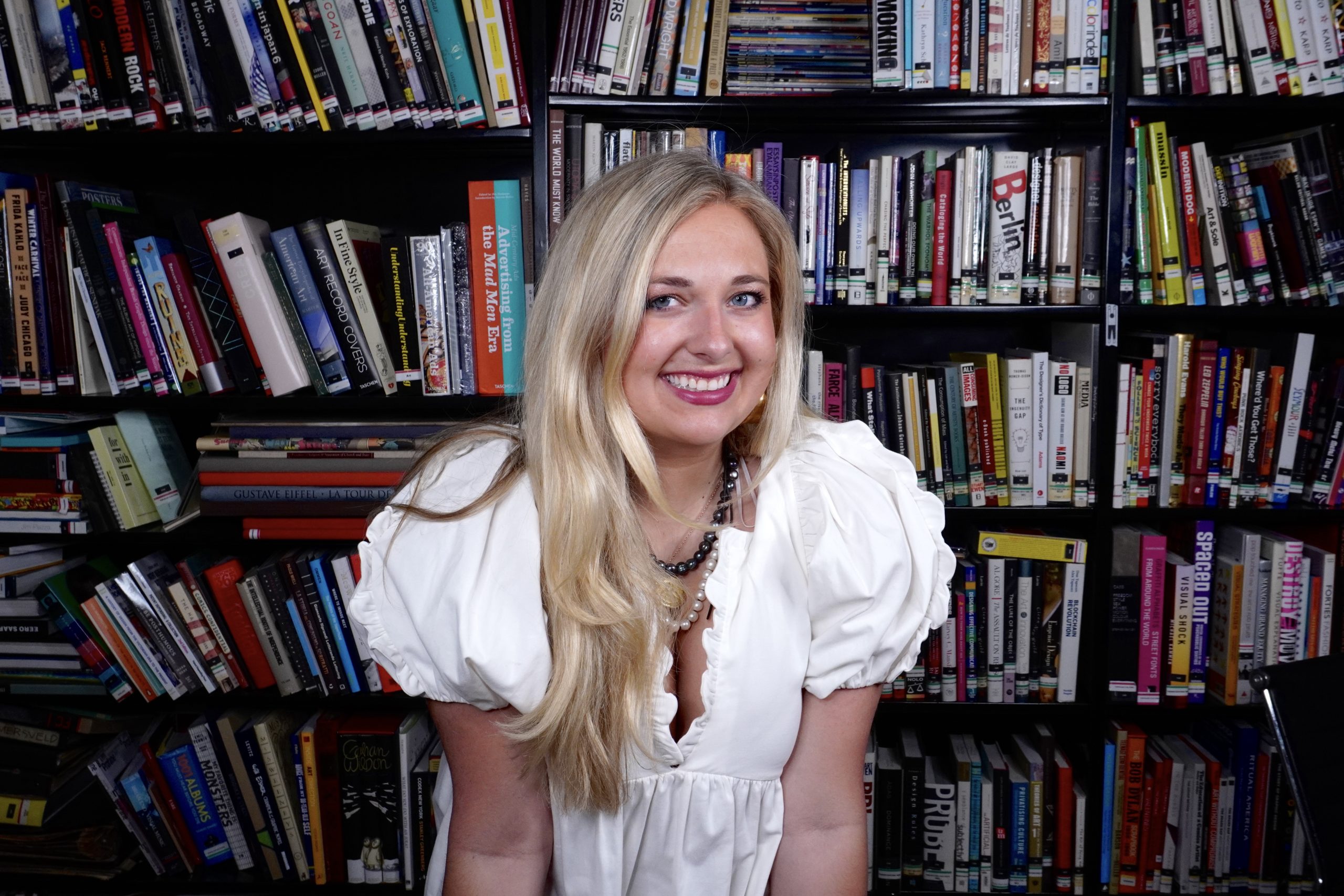 blonde woman posing in front of bookshelf