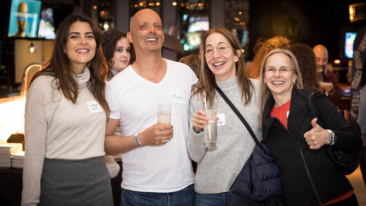 group of four people at a bar holding drinks