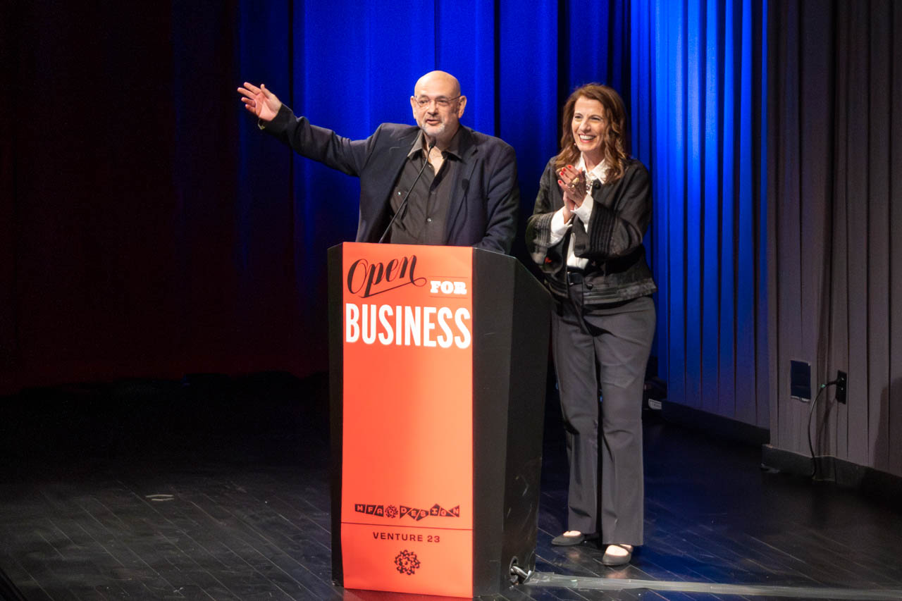 woman and a man standing at a podium delivering a presentation
