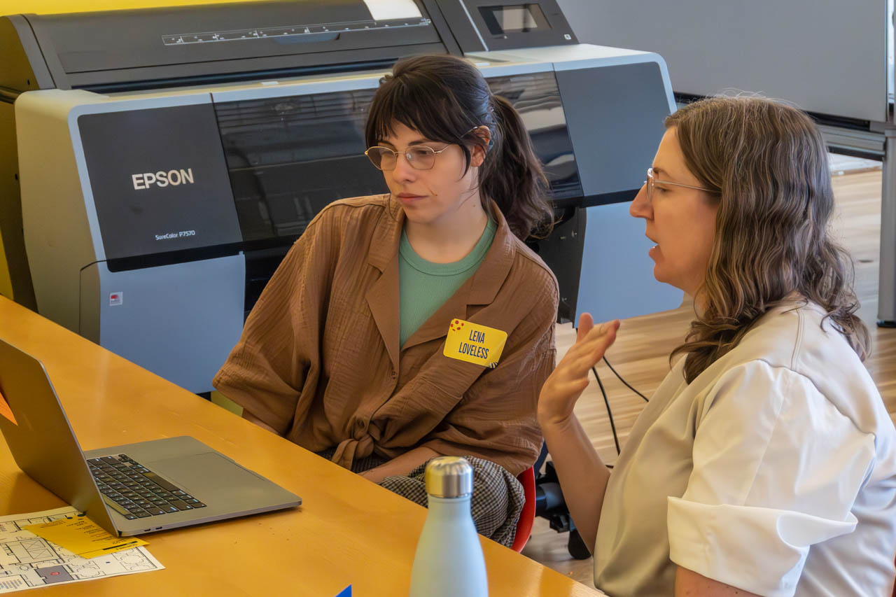 two people talking next to a computer