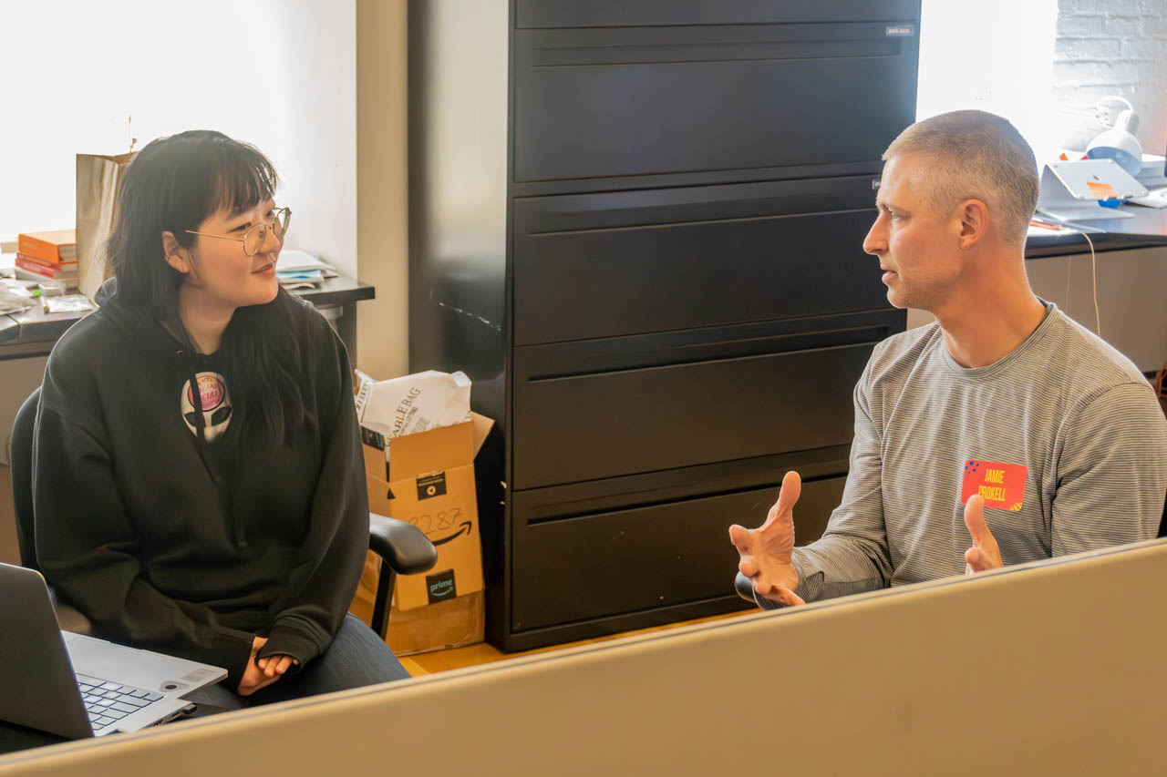 two people talking next to a computer