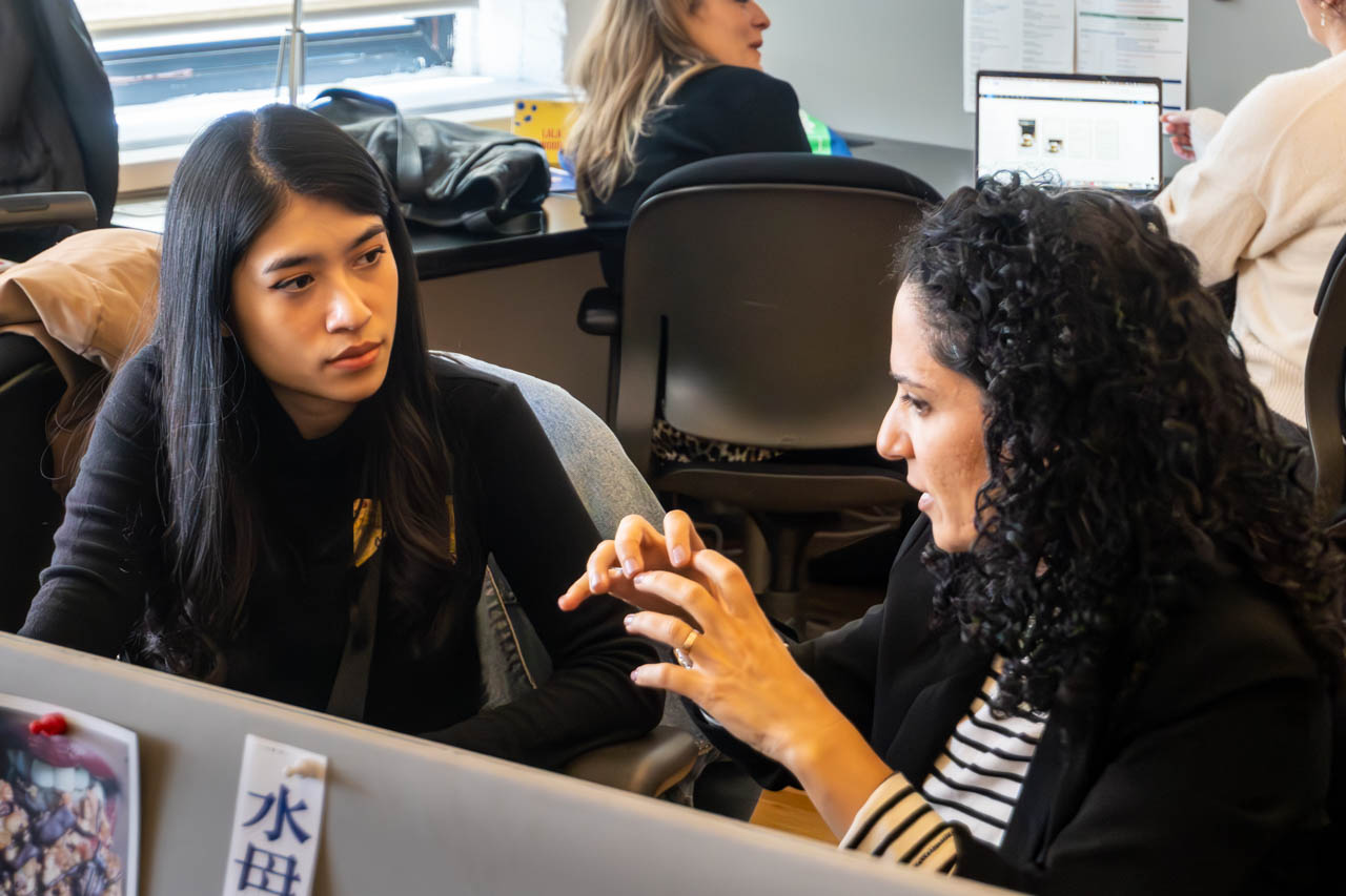 two people talking next to a computer