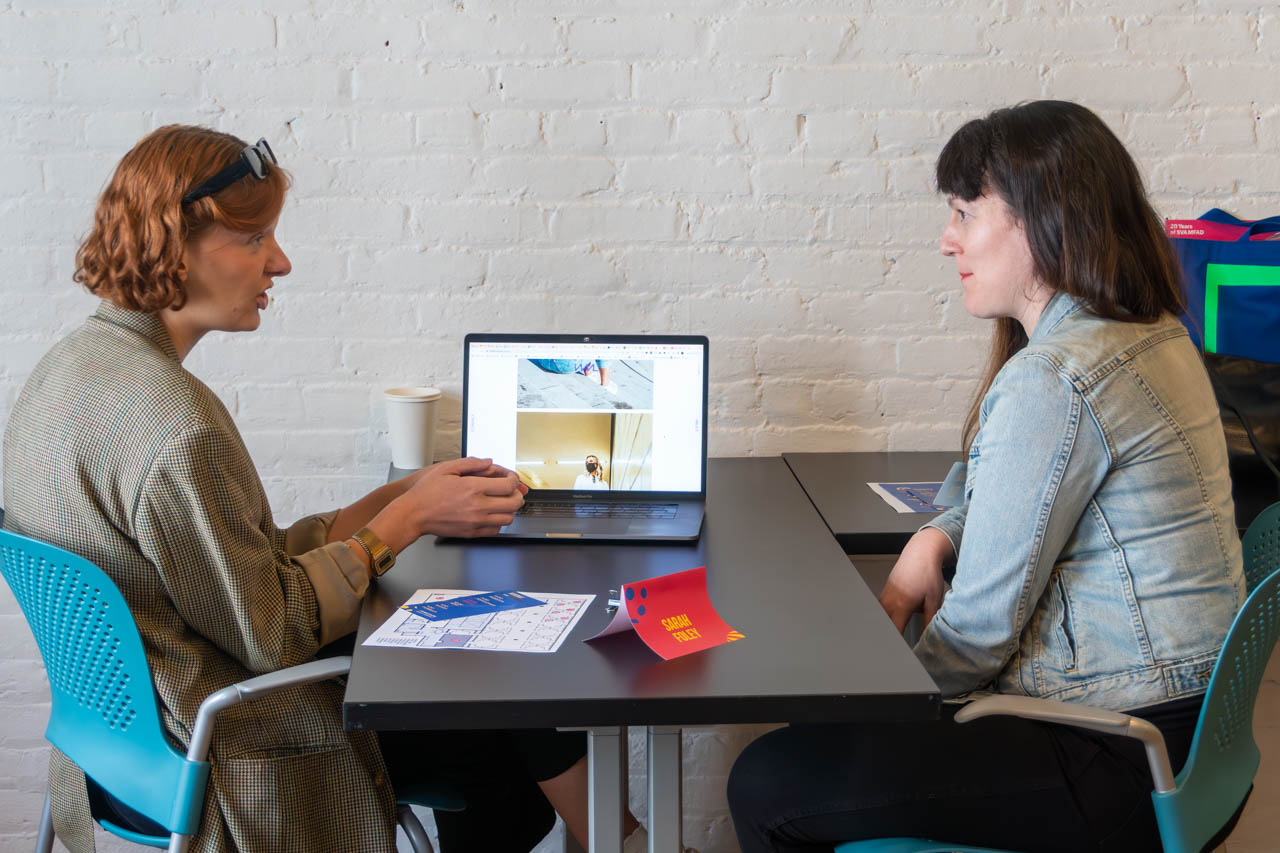 two people talking next to a computer