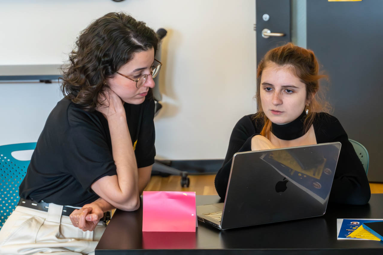 two people talking next to a computer