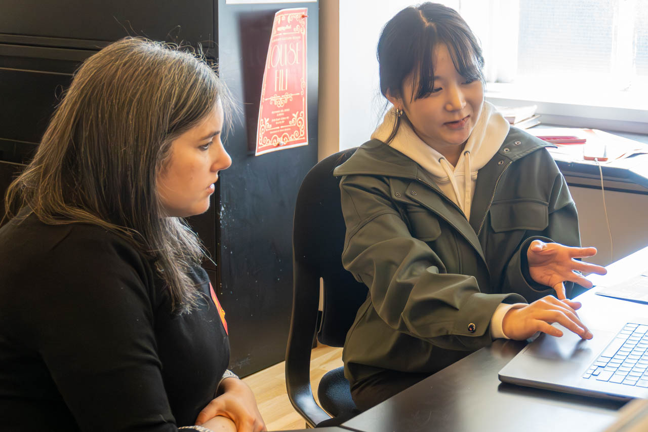 two people talking next to a computer