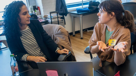 two people talking next to a computer