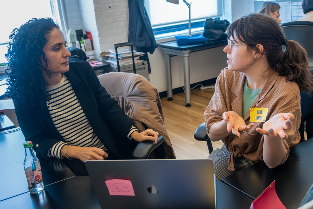 two people talking next to a computer