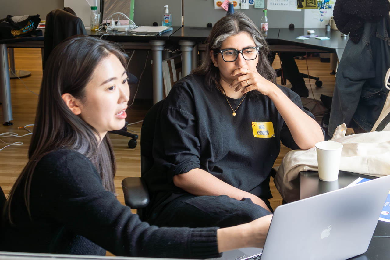 two people talking next to a computer