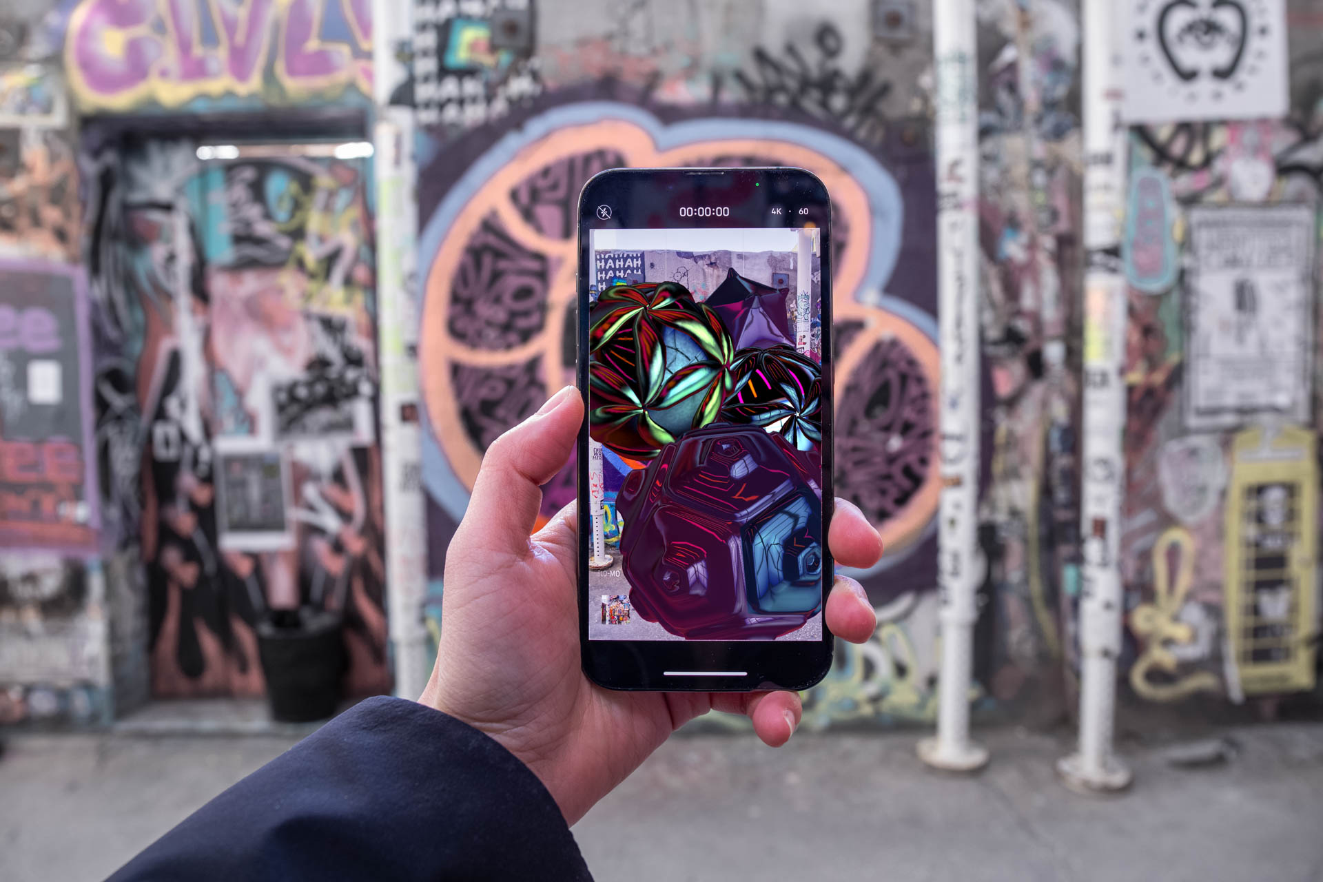 a hand holding an iphone looking at graffitti