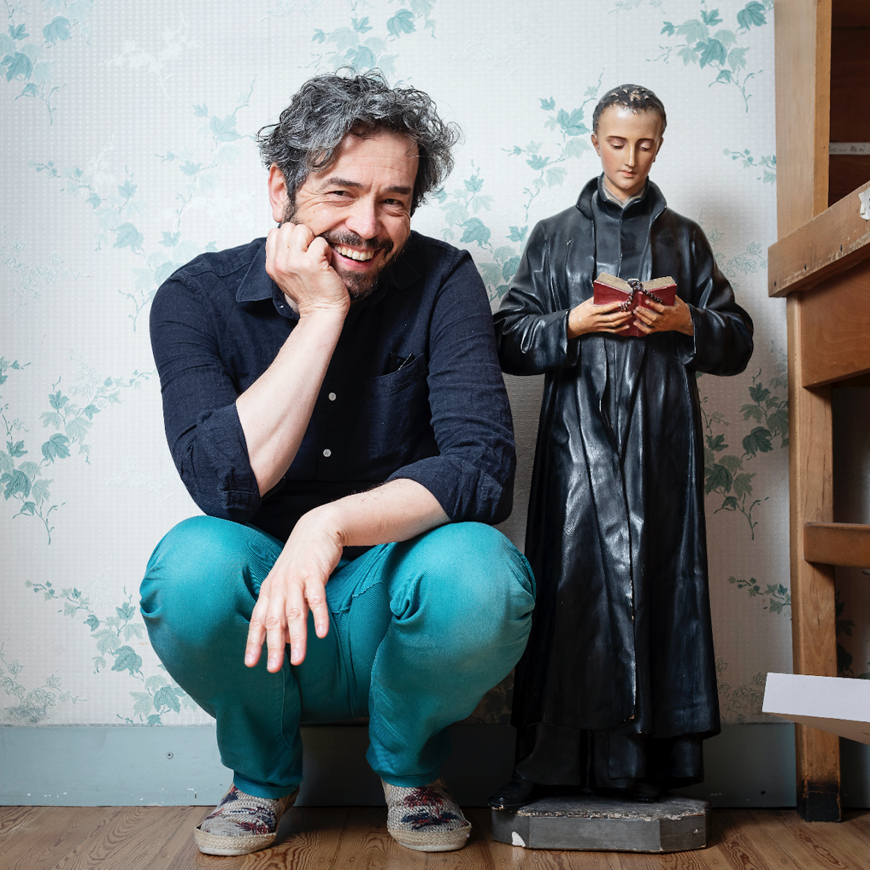 portrait of a man smiling next to a small statue