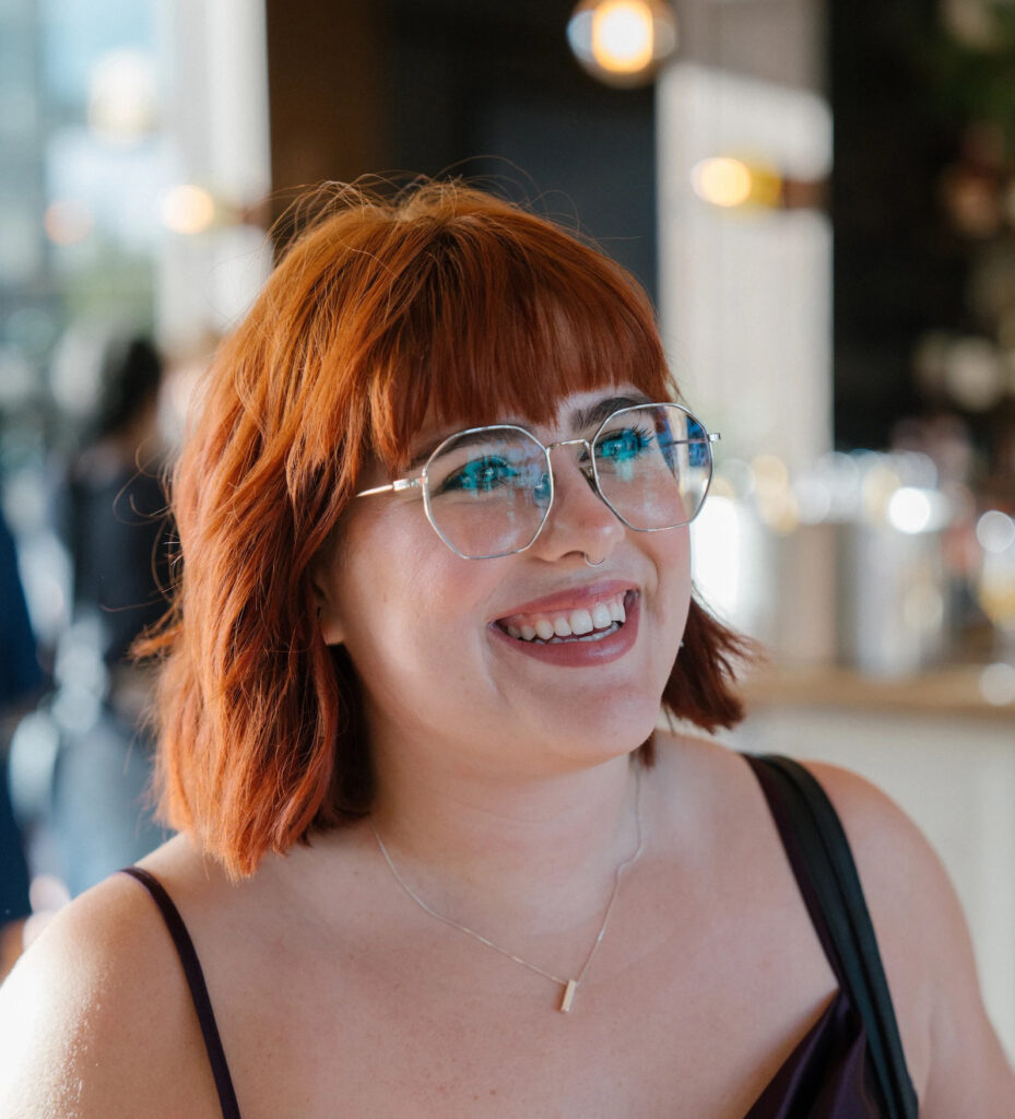 girl with red hair and glasses smiling at the camera