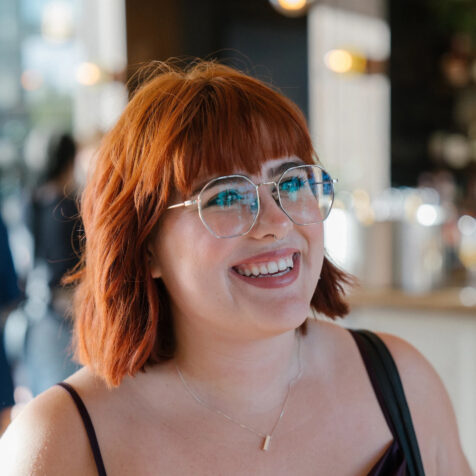 girl with red hair wearing glasses smiling