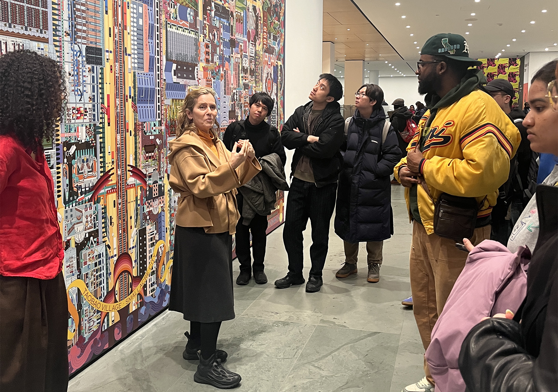 woman standing in front of an art piece explaining it to a crowd