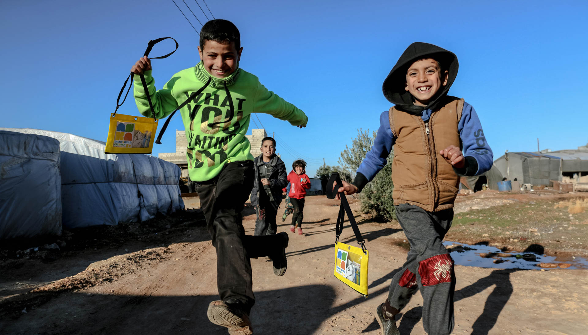 two kids running holding bags with the ANKA logo