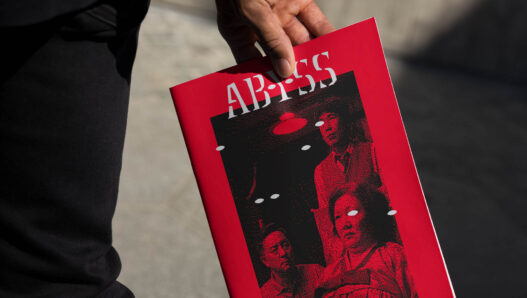 hand holding a book with the Abyss logo (red)