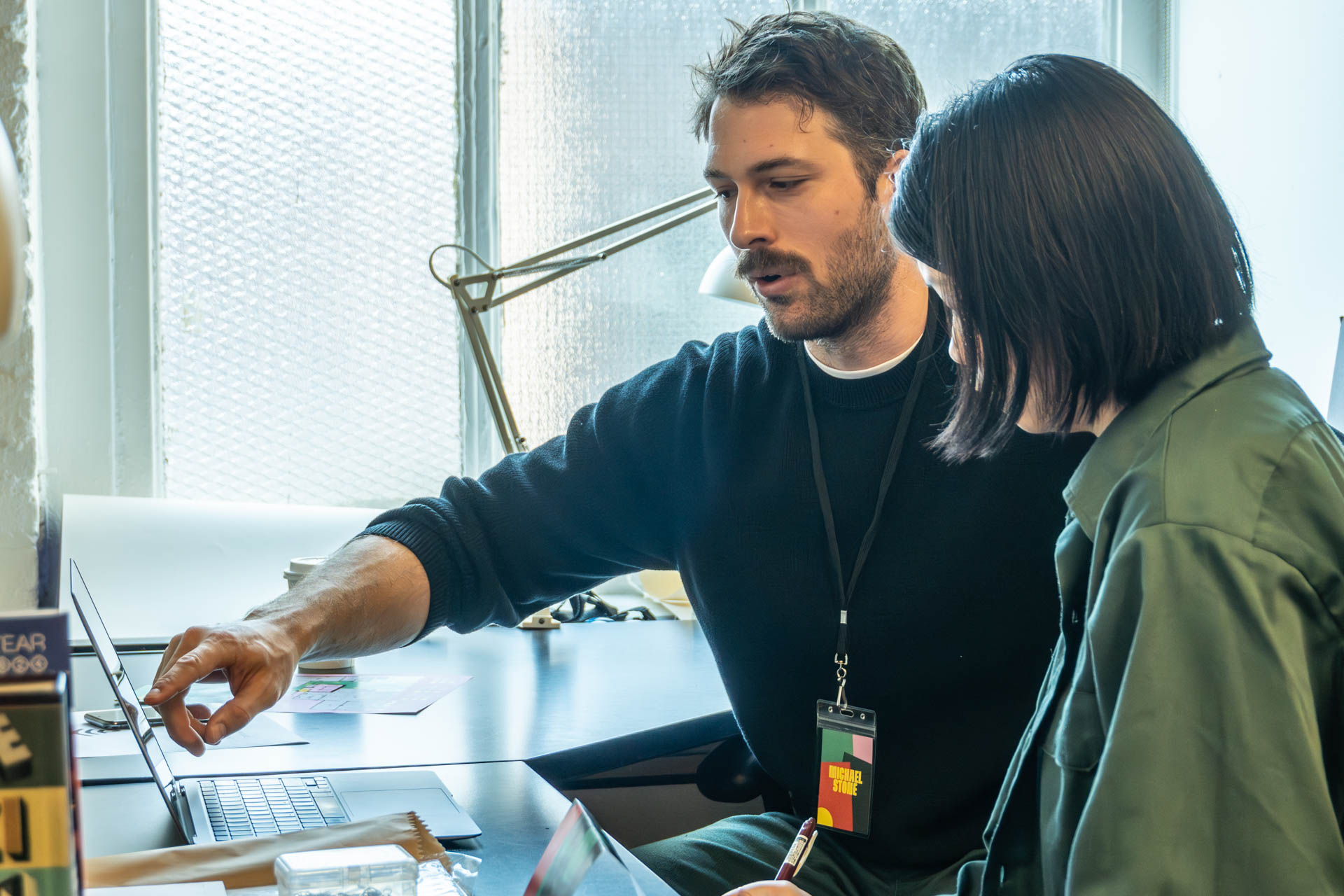 two people talking and looking at a computer