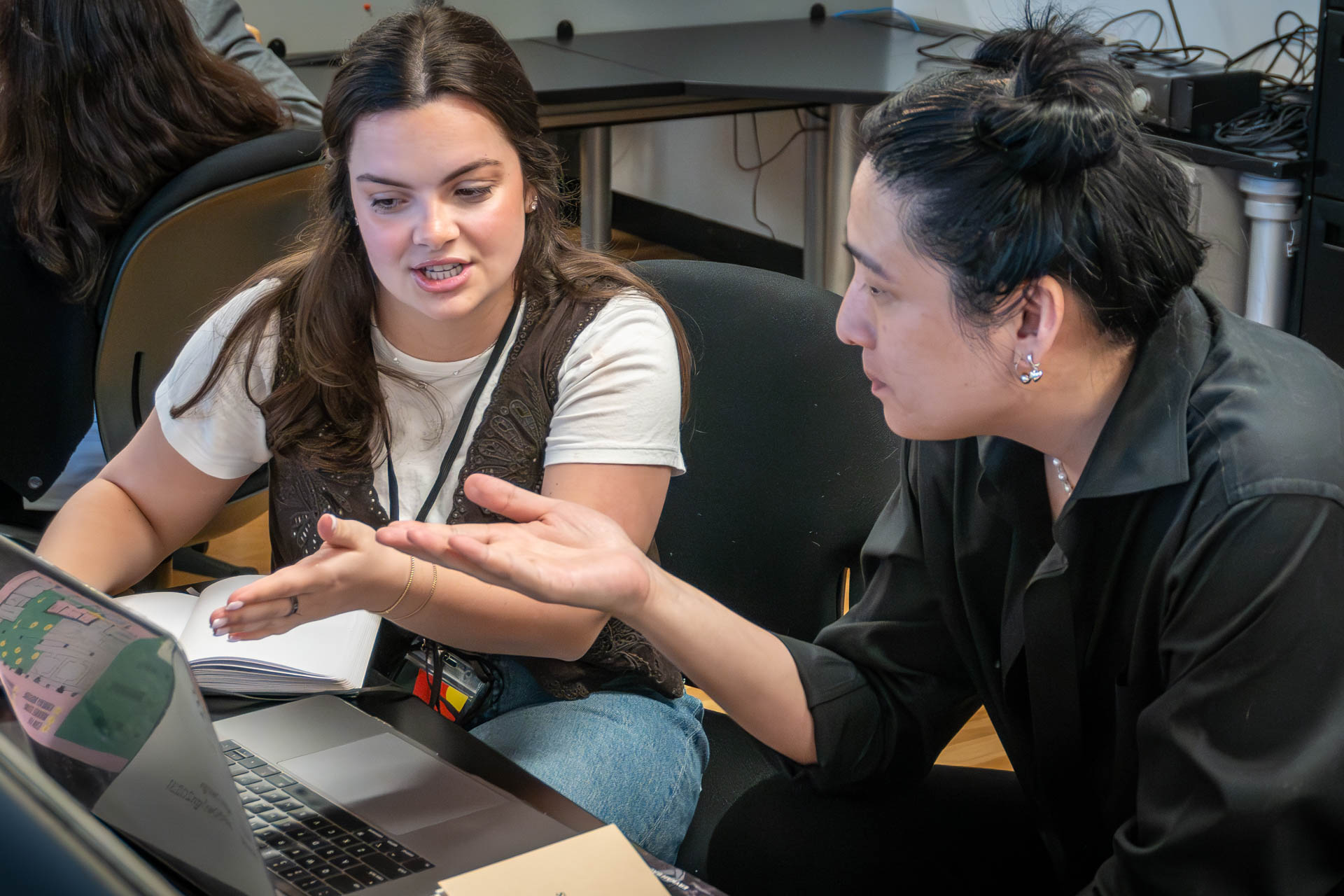 two people talking and looking at a computer