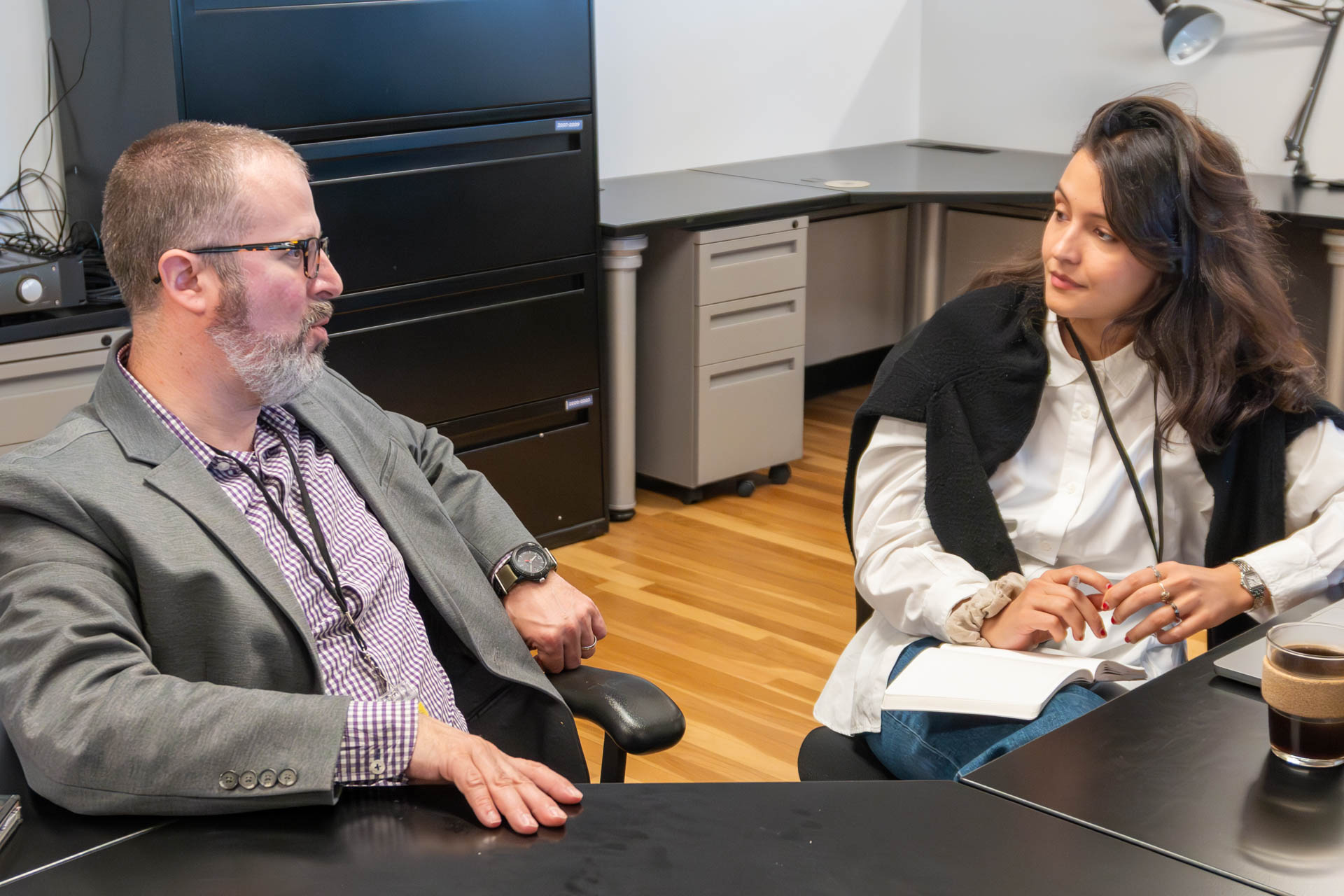 two people talking and looking at a computer