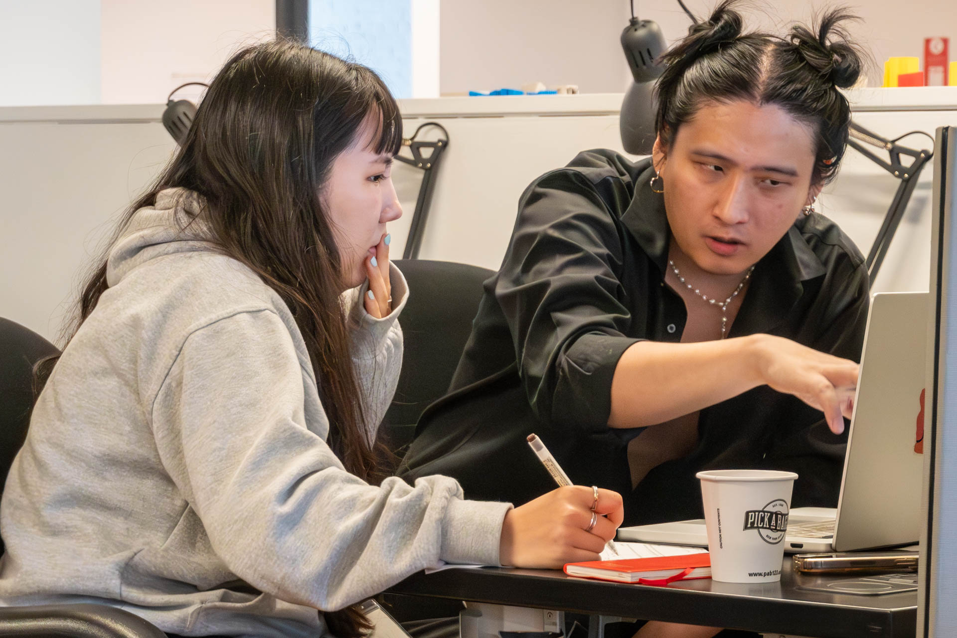 two people talking and looking at a computer