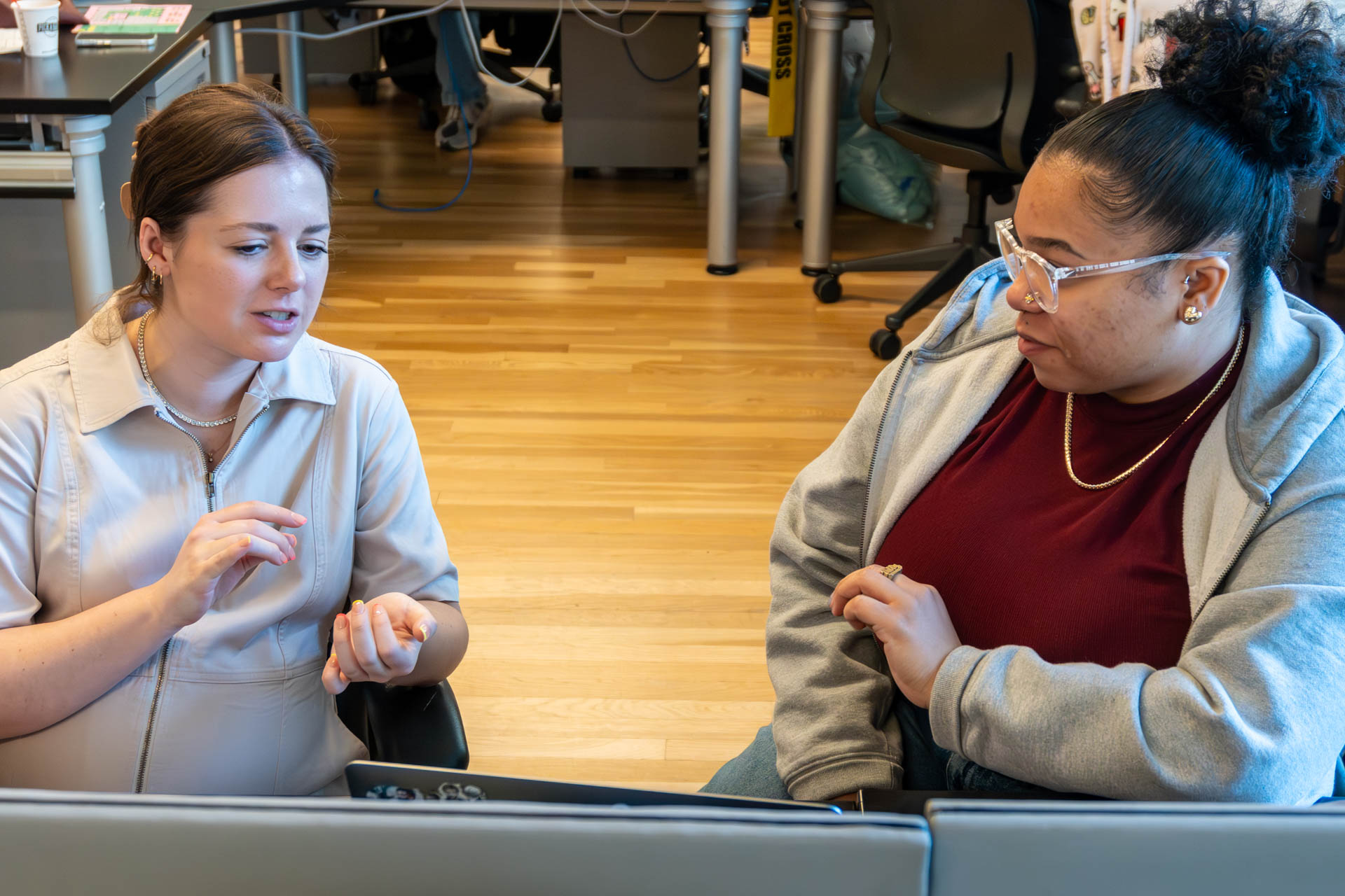 two people talking and looking at a computer