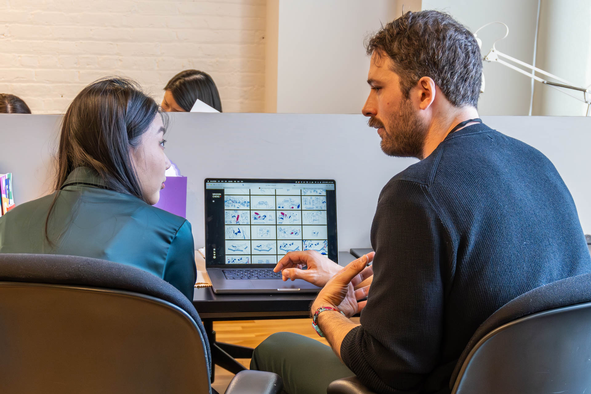 two people talking and looking at a computer