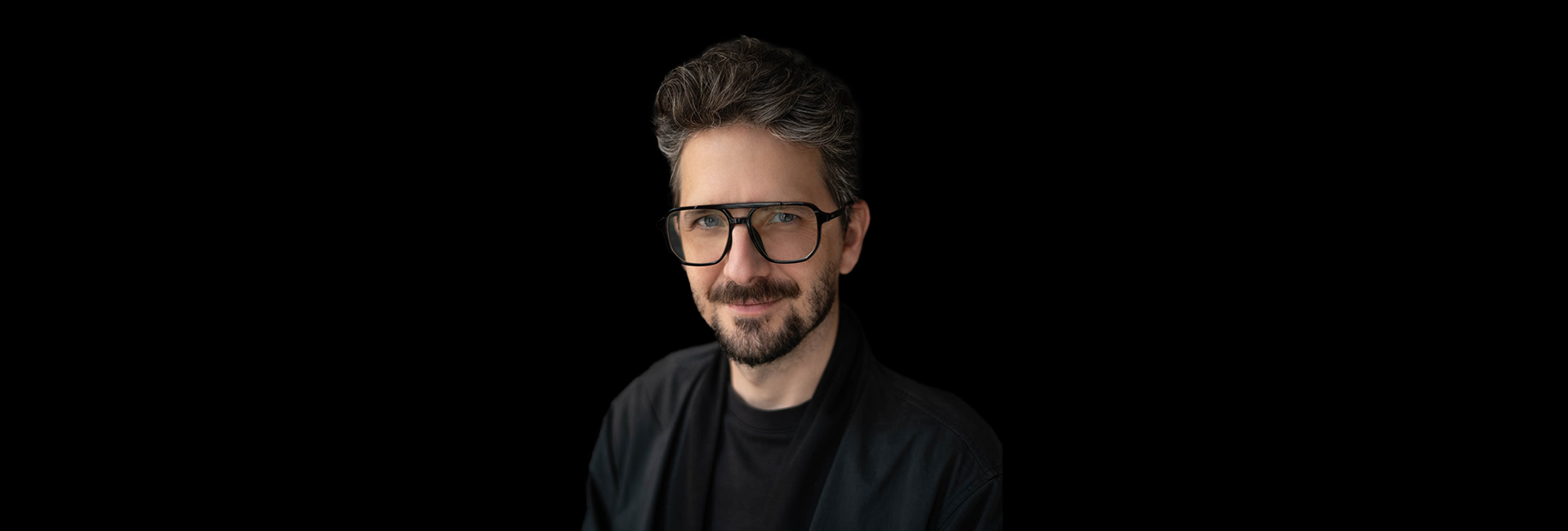 portrait of a man with glasses on black background. Randy Hunt