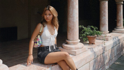 woman with long hair sitting in a colonade