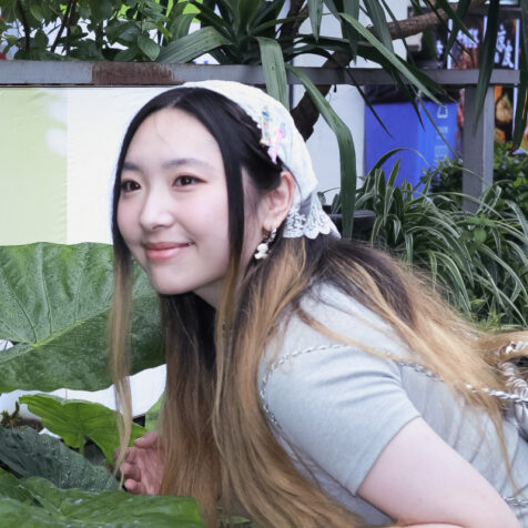 a woman with long hair with plants in the background