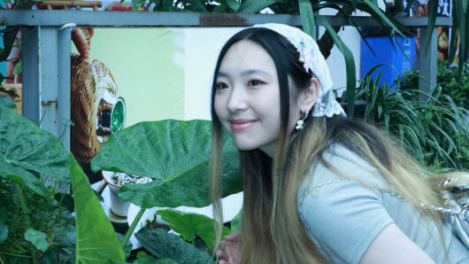 a woman with long hair with plants in the background