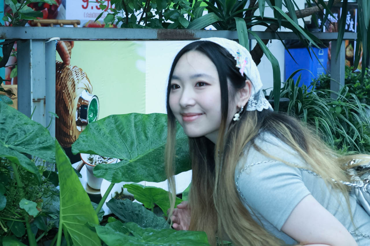 a woman with long hair with plants in the background