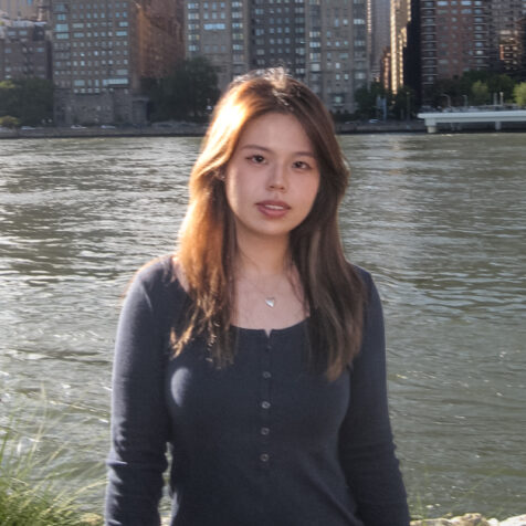 a woman with long hair with a river and buildings in the background