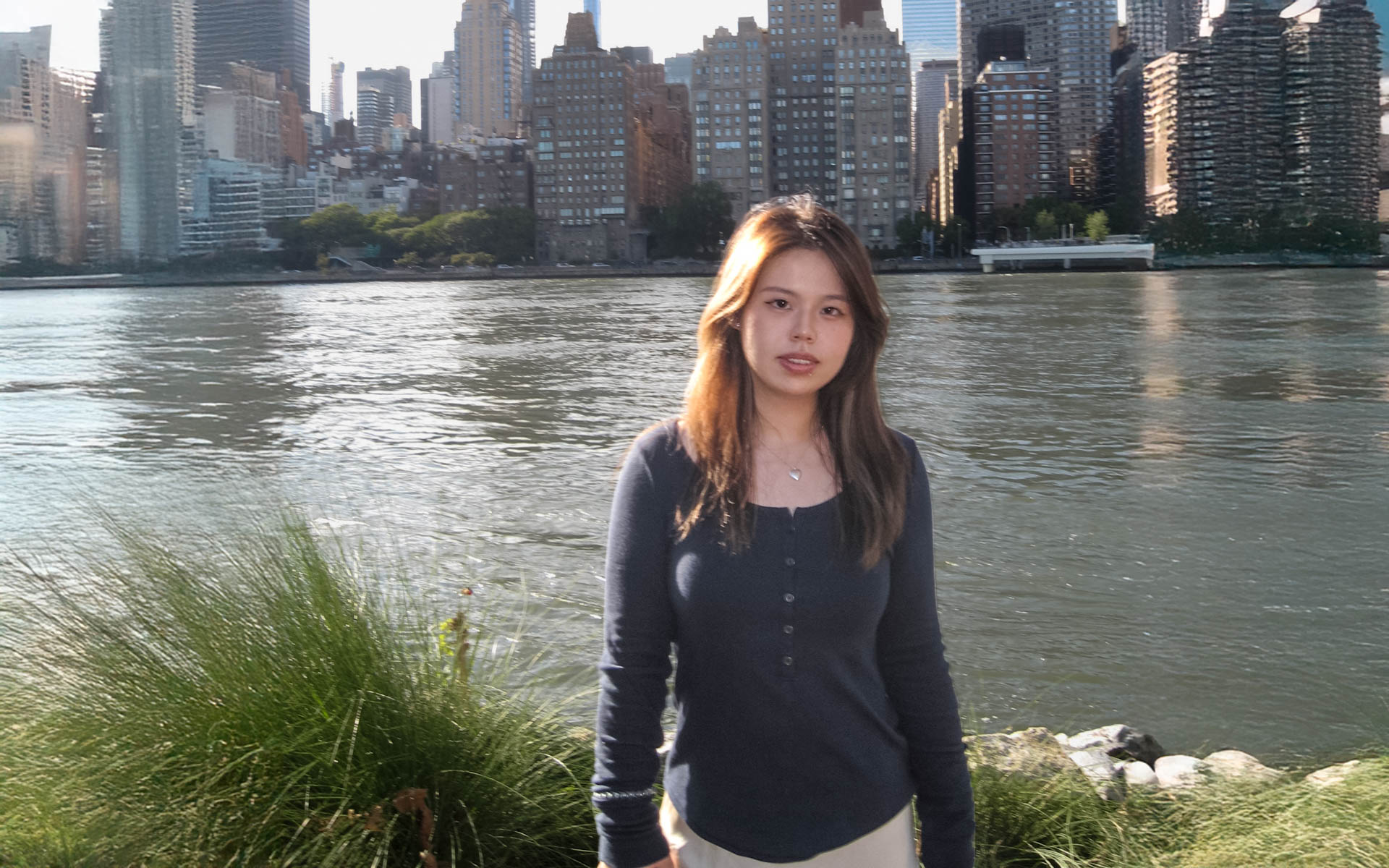 a woman with long hair with a river and buildings in the background