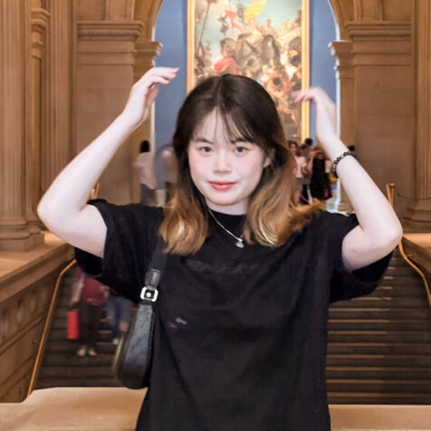 a woman in a marble room with hands above her head -square photo