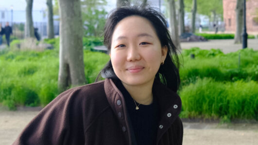 a woman looking at the camera with a park in the background