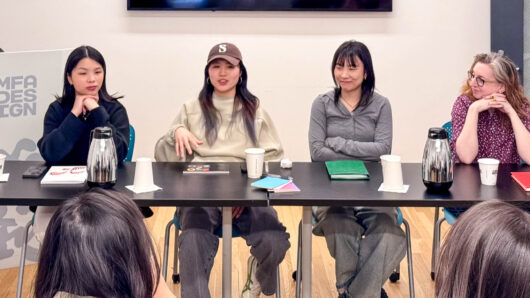 a panel of four women speak to a class of people at their desks