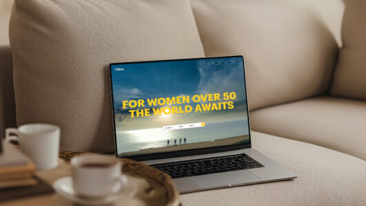 a laptop open on a couch. the screen showing says something about older women and that the world awaits