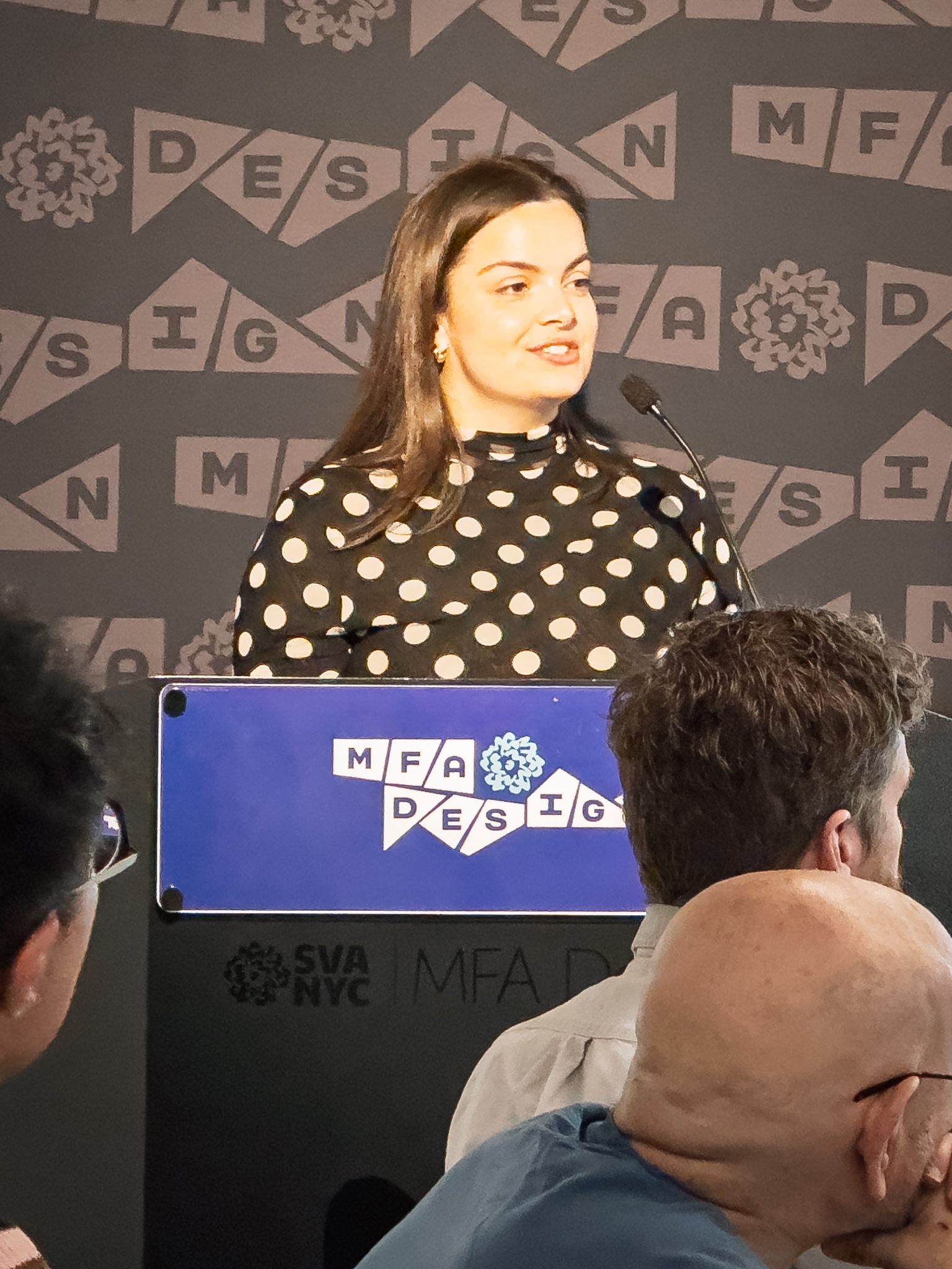 Woman at a podium with microphone, delivering a slide presentation